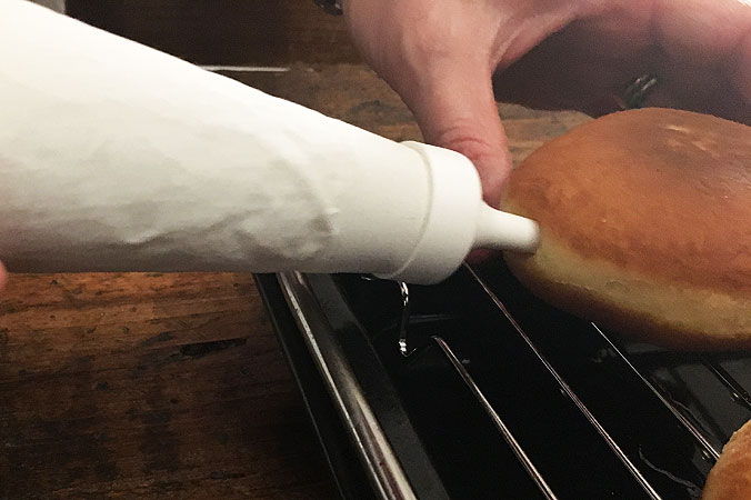 Krapfen selber backen: Die Krapfen mit passierter Marmelade füllen